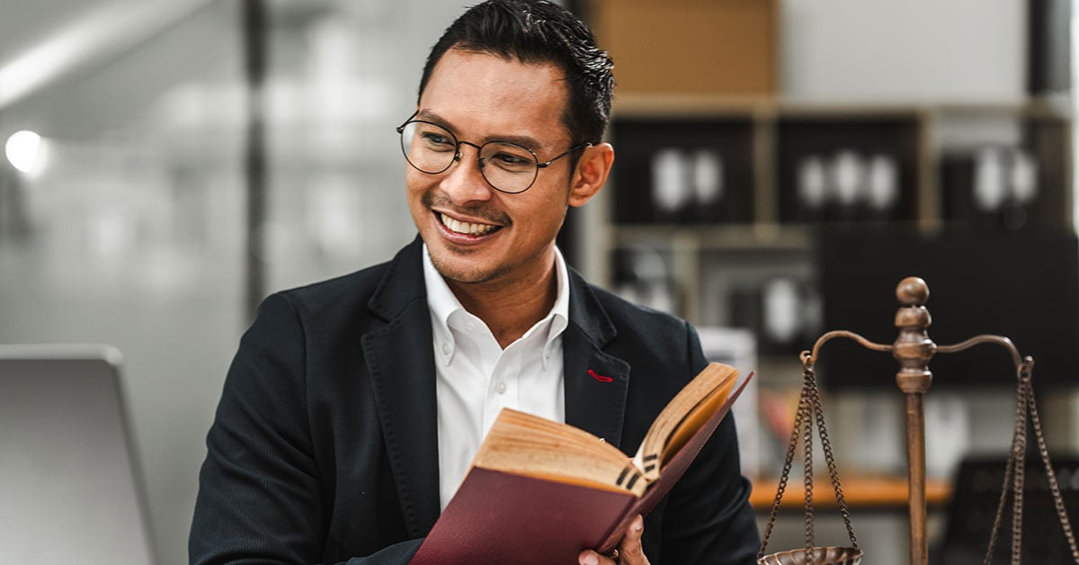 Smiling law professional sitting in an office with an open book