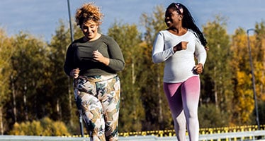 Two women smiling and jogging together